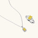 Yellow moissanite jewelry set with emerald-cut stones in sterling silver halo settings on white background.