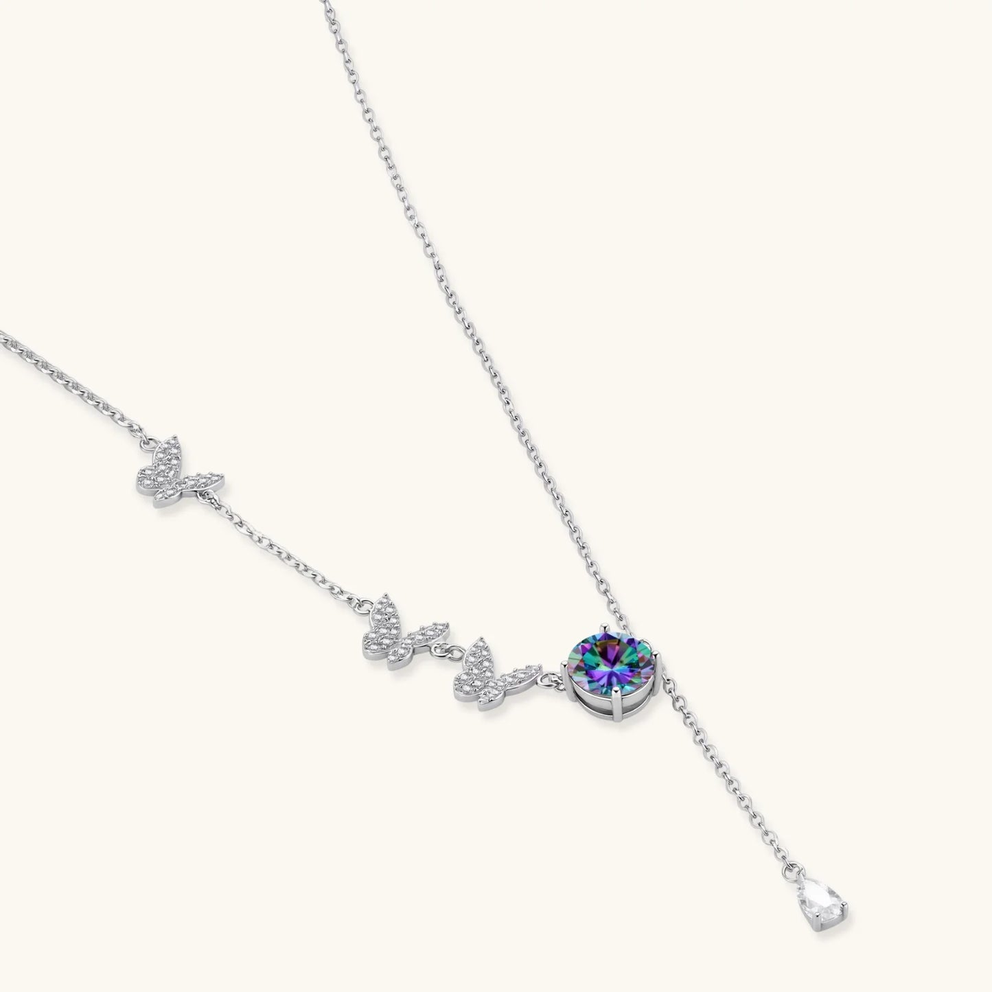 Sterling silver jewelry set with rainbow moissanite stones in clover and butterfly designs on cream background