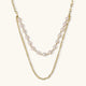Layered gold chain necklace with organic baroque freshwater pearls and adjustable length on cream background